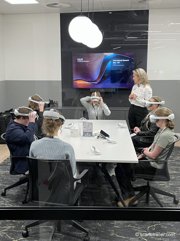 Group of girls gathered around a meeting table using VR headsets.