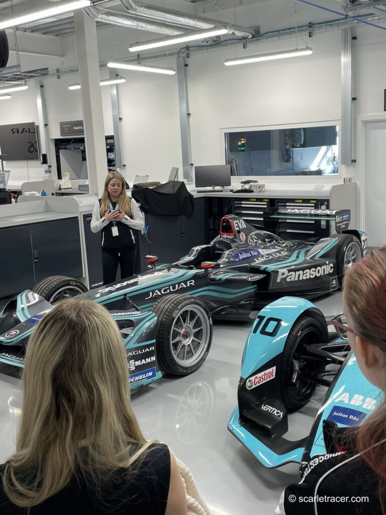 Jaguar TCS team member showing girls a 1st generation Jaguar TCS race car.